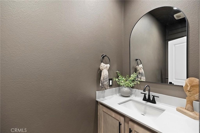 bathroom with a textured wall and vanity