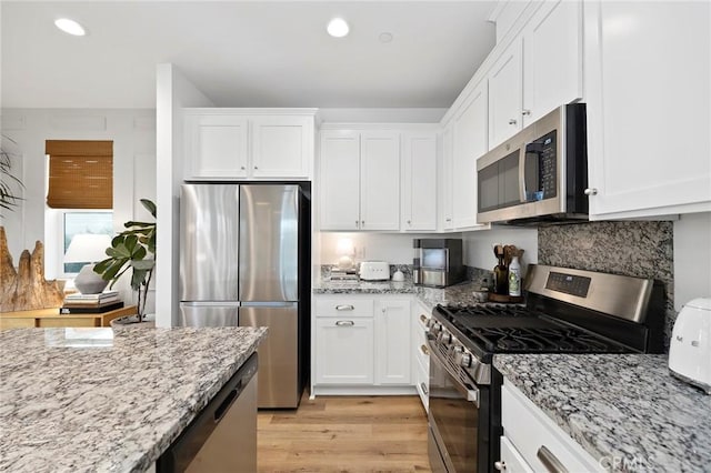 kitchen with light wood-type flooring, appliances with stainless steel finishes, and white cabinets