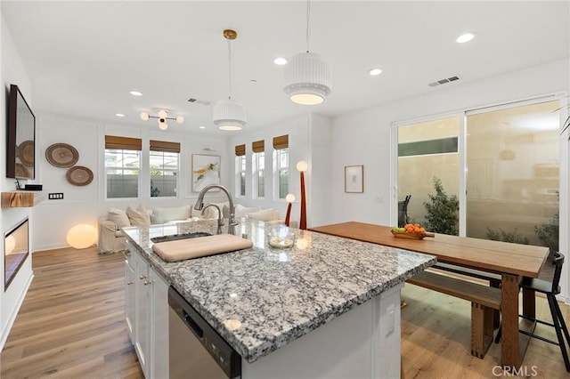 kitchen with visible vents, dishwasher, open floor plan, light wood-type flooring, and a sink