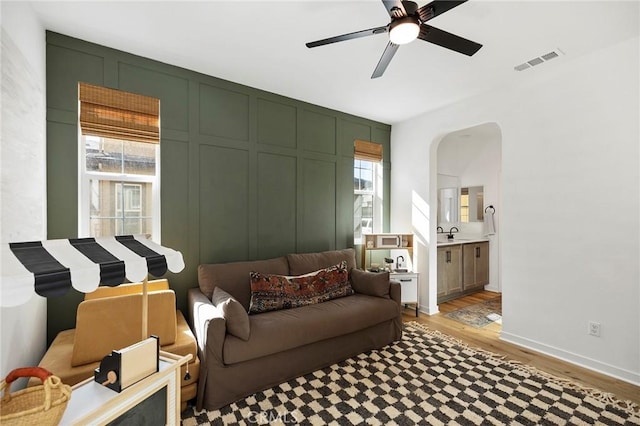 living area featuring light wood-style floors, a healthy amount of sunlight, visible vents, and a decorative wall