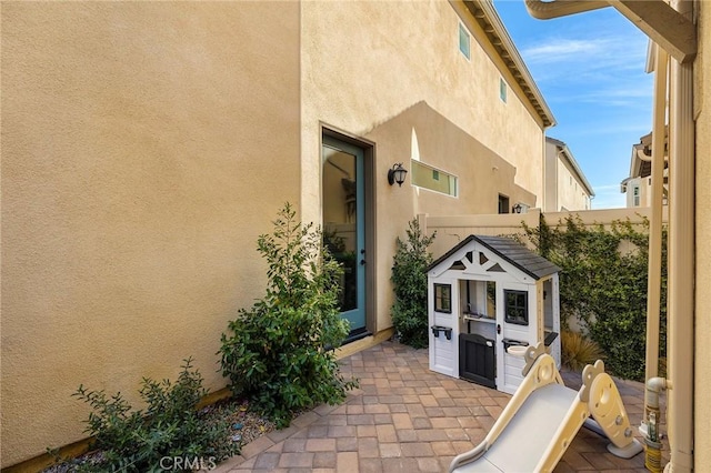 exterior space featuring a patio area, fence, and stucco siding