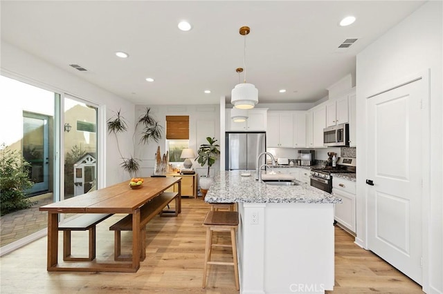 kitchen featuring light wood-type flooring, visible vents, stainless steel appliances, and a sink