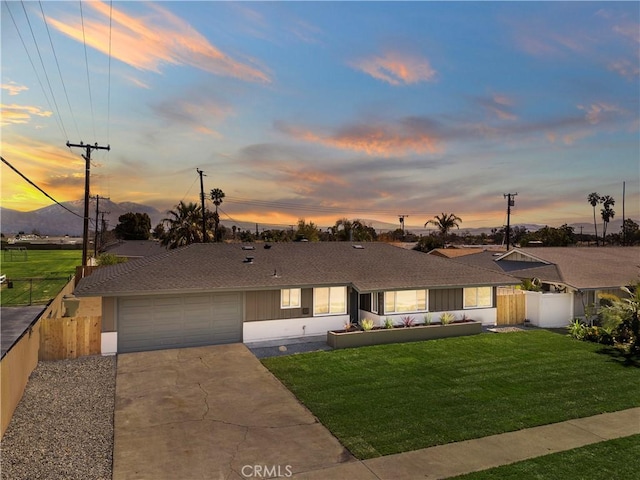 view of front of home with a garage, fence, concrete driveway, a yard, and roof with shingles