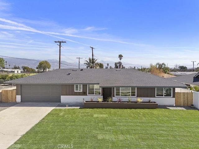 ranch-style home featuring driveway, roof with shingles, an attached garage, fence, and a front lawn