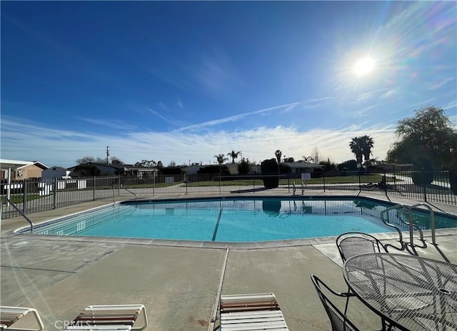 pool with a patio area and fence