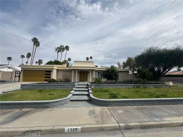 view of front facade featuring a garage, driveway, a front lawn, and stucco siding