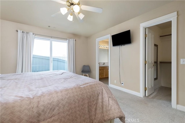 bedroom featuring visible vents, a walk in closet, baseboards, ceiling fan, and light colored carpet