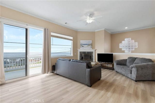 living room featuring visible vents, a ceiling fan, light wood-type flooring, and ornamental molding