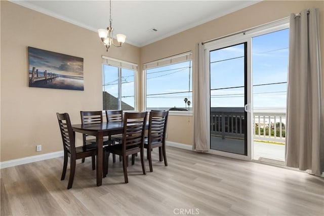 dining area featuring a chandelier, baseboards, crown molding, and light wood-style floors