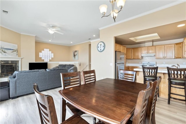 dining space with light wood finished floors, visible vents, ceiling fan with notable chandelier, and ornamental molding