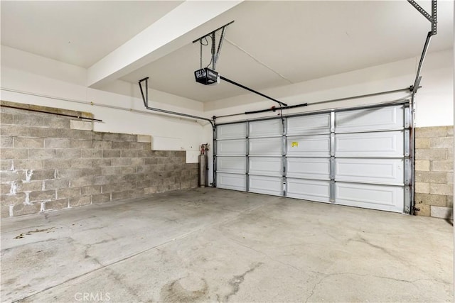 garage featuring a garage door opener and concrete block wall