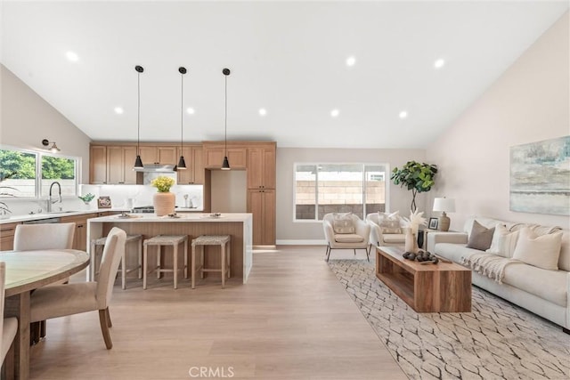 living room featuring baseboards, high vaulted ceiling, recessed lighting, and light wood-style floors