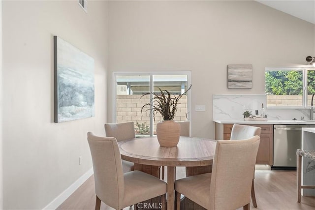 dining space featuring lofted ceiling, light wood-style flooring, visible vents, and baseboards