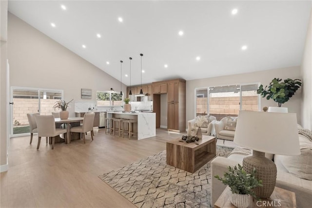 living room featuring light wood-style floors, recessed lighting, a healthy amount of sunlight, and high vaulted ceiling