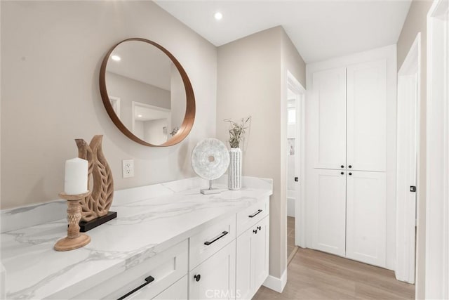 bathroom with wood finished floors, vanity, and recessed lighting