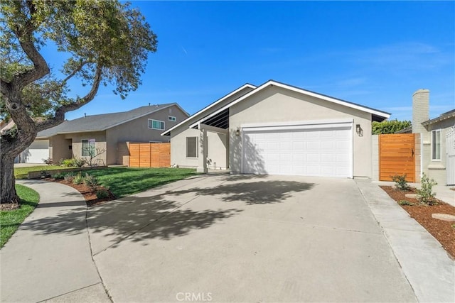 view of front of house with a garage, concrete driveway, fence, and stucco siding