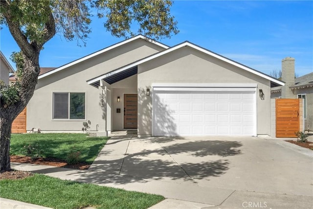 view of front of house with a garage, driveway, a front yard, and stucco siding