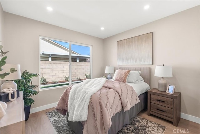 bedroom featuring multiple windows, light wood-style flooring, and baseboards