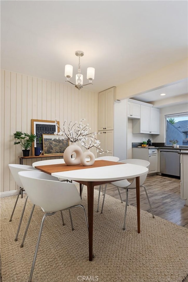 dining area with light wood-type flooring and an inviting chandelier