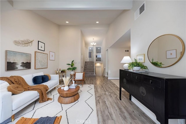 living room with stairway, beam ceiling, visible vents, and wood finished floors