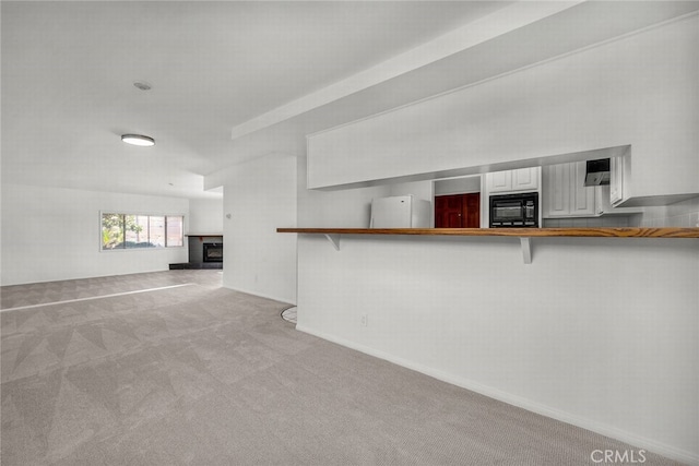 unfurnished living room with carpet floors and a fireplace with raised hearth