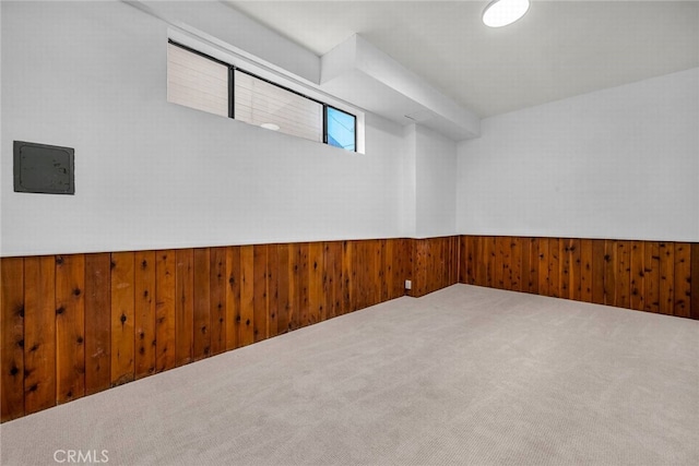 carpeted spare room with wood walls and wainscoting