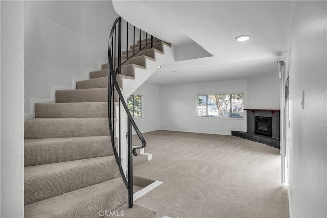 stairway with carpet and a fireplace