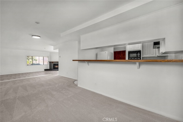 unfurnished living room with a warm lit fireplace and carpet