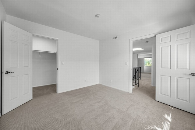 unfurnished bedroom featuring carpet, visible vents, a walk in closet, and a closet