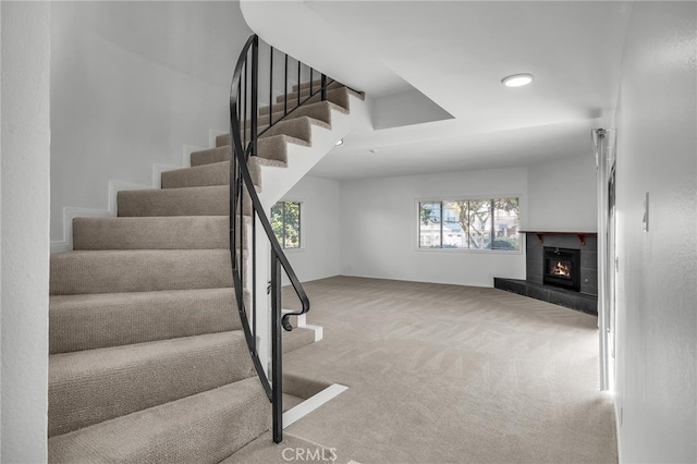 staircase featuring carpet floors and a tile fireplace