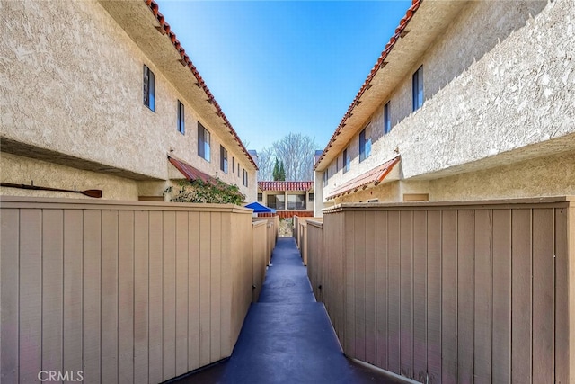 view of property exterior featuring a tile roof, fence, and stucco siding