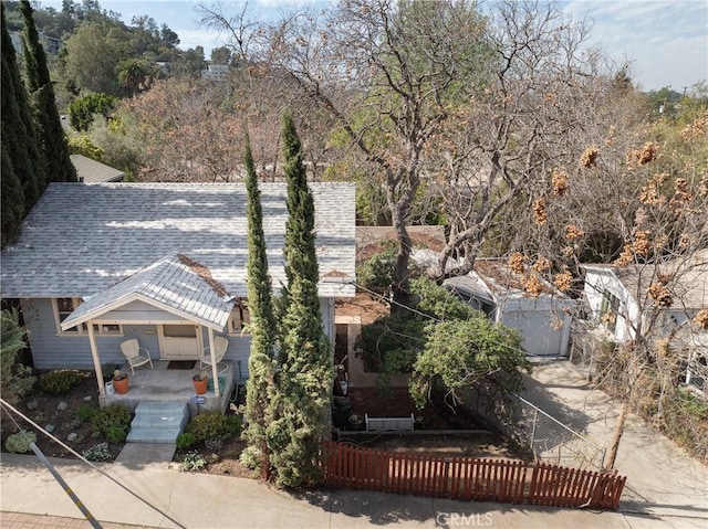 view of front facade featuring a fenced front yard, a porch, and roof with shingles