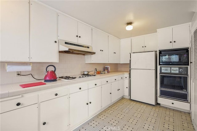 kitchen featuring white cabinets, light floors, under cabinet range hood, black appliances, and a warming drawer