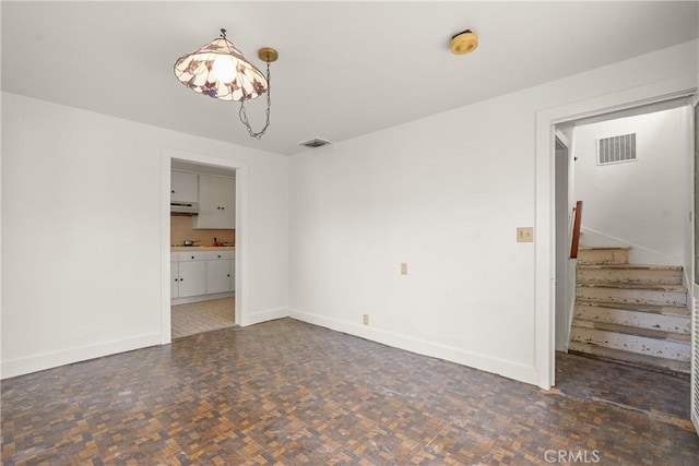 unfurnished room featuring stairway, visible vents, and baseboards