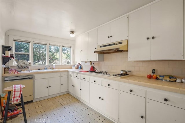 kitchen featuring white appliances, white cabinets, light floors, under cabinet range hood, and a sink