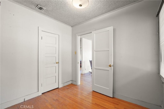 spare room with visible vents, a textured ceiling, and light wood finished floors