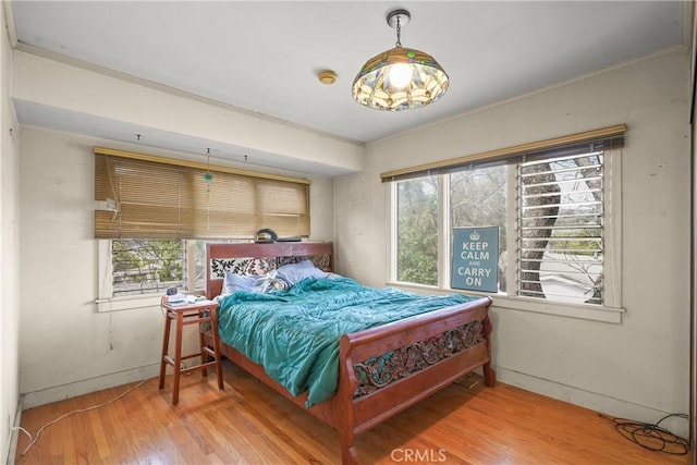 bedroom with multiple windows, ornamental molding, and wood finished floors