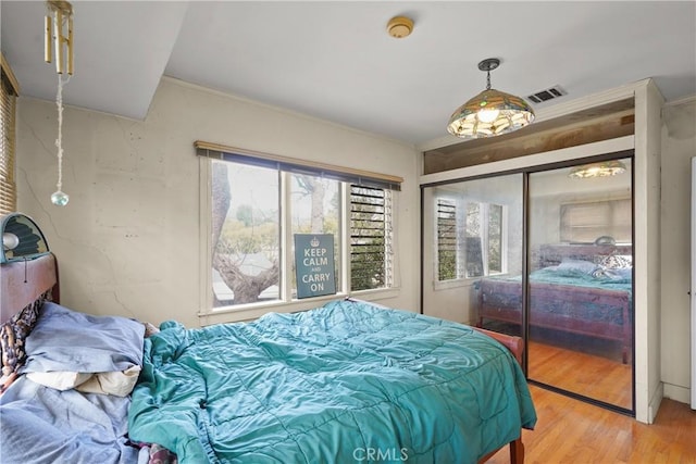 bedroom featuring light wood-type flooring, a closet, and visible vents