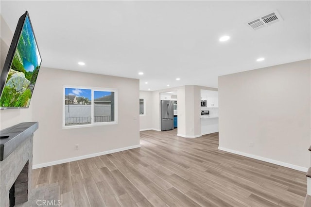 unfurnished living room featuring light wood finished floors, a fireplace, visible vents, and recessed lighting