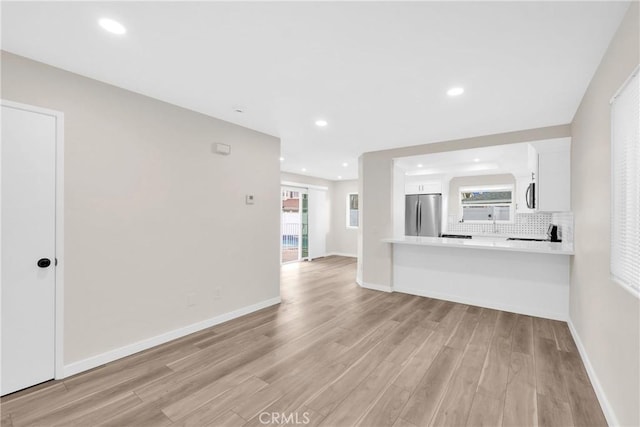 unfurnished living room featuring recessed lighting, baseboards, and light wood finished floors