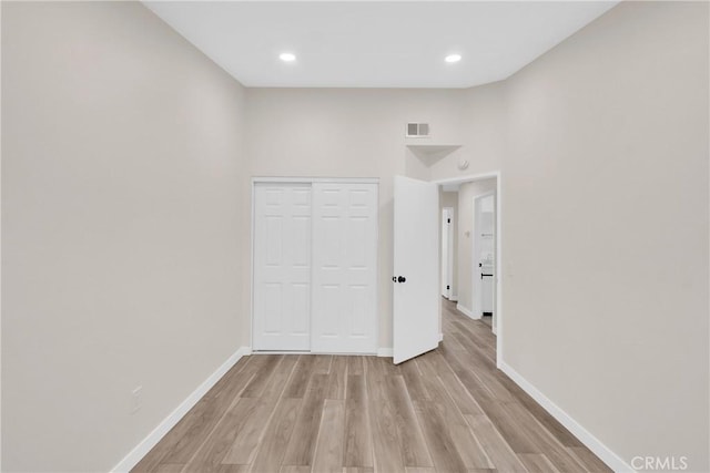 unfurnished bedroom featuring recessed lighting, a closet, visible vents, light wood-style flooring, and baseboards