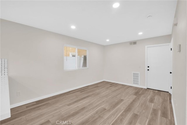 empty room featuring light wood finished floors, recessed lighting, visible vents, and baseboards