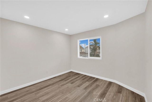 empty room featuring recessed lighting, wood finished floors, and baseboards