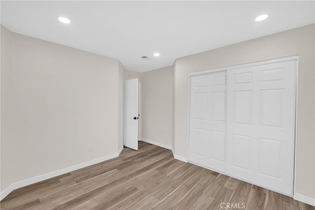 unfurnished bedroom with recessed lighting, light wood-style flooring, and baseboards