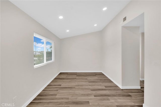 spare room featuring recessed lighting, wood finished floors, visible vents, and baseboards