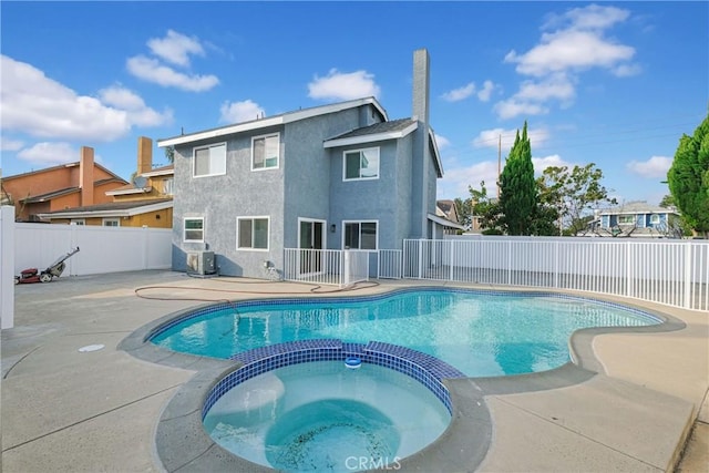 view of pool featuring a patio area, a pool with connected hot tub, central AC unit, and a fenced backyard