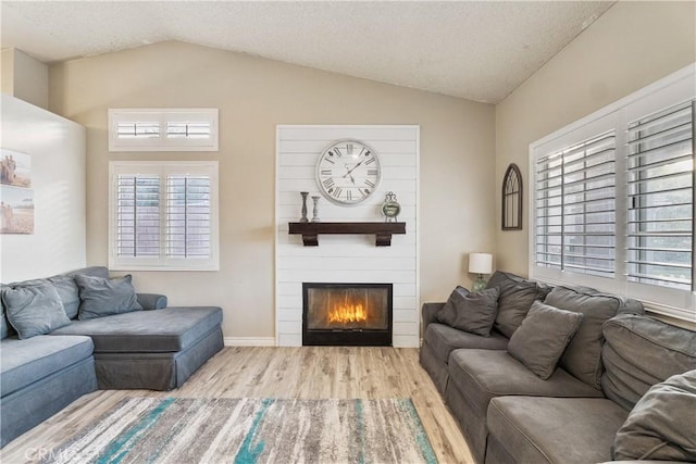 living area featuring lofted ceiling, plenty of natural light, and wood finished floors