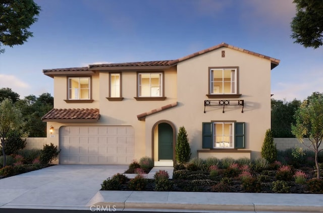 mediterranean / spanish house with concrete driveway, a tiled roof, an attached garage, fence, and stucco siding