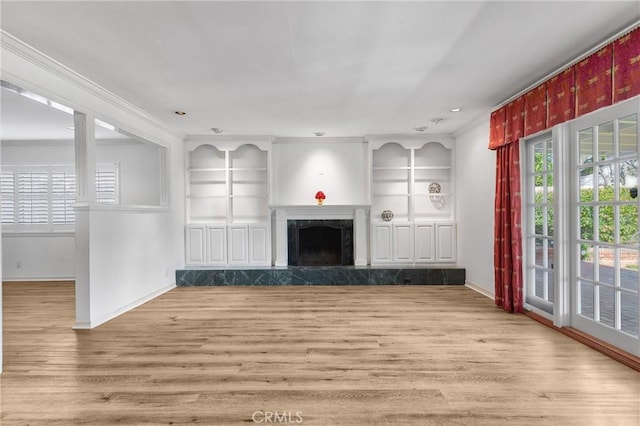 unfurnished living room with built in shelves, a fireplace, wood finished floors, and baseboards