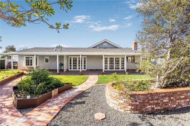 rear view of property featuring french doors, a chimney, and stucco siding